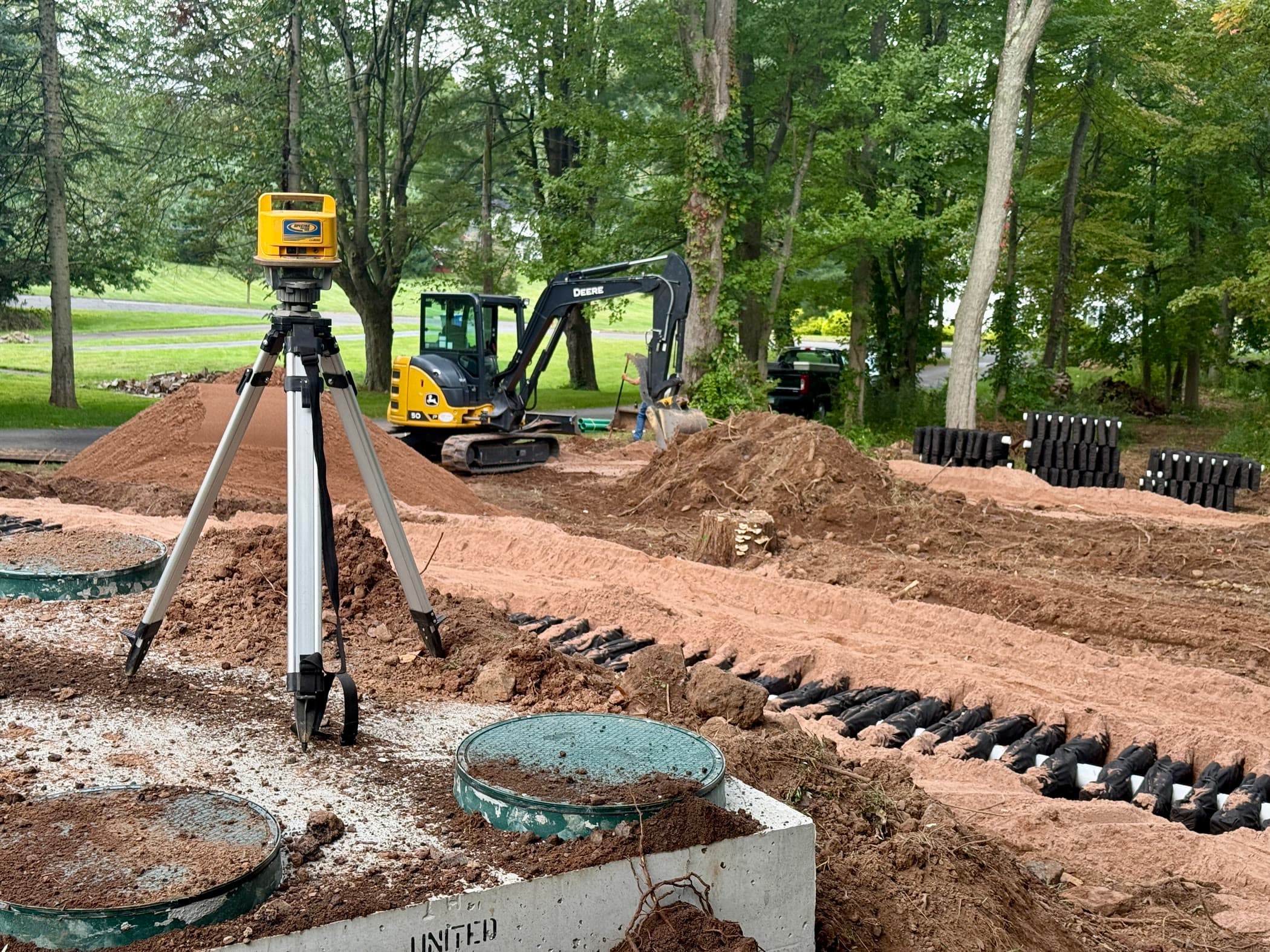 New septic system installation in progress on a Connecticut Shoreline lot, with chambers, tank lids, and an excavator.